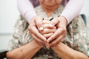 Caregiver holding hands of Asian elderly woman patient
